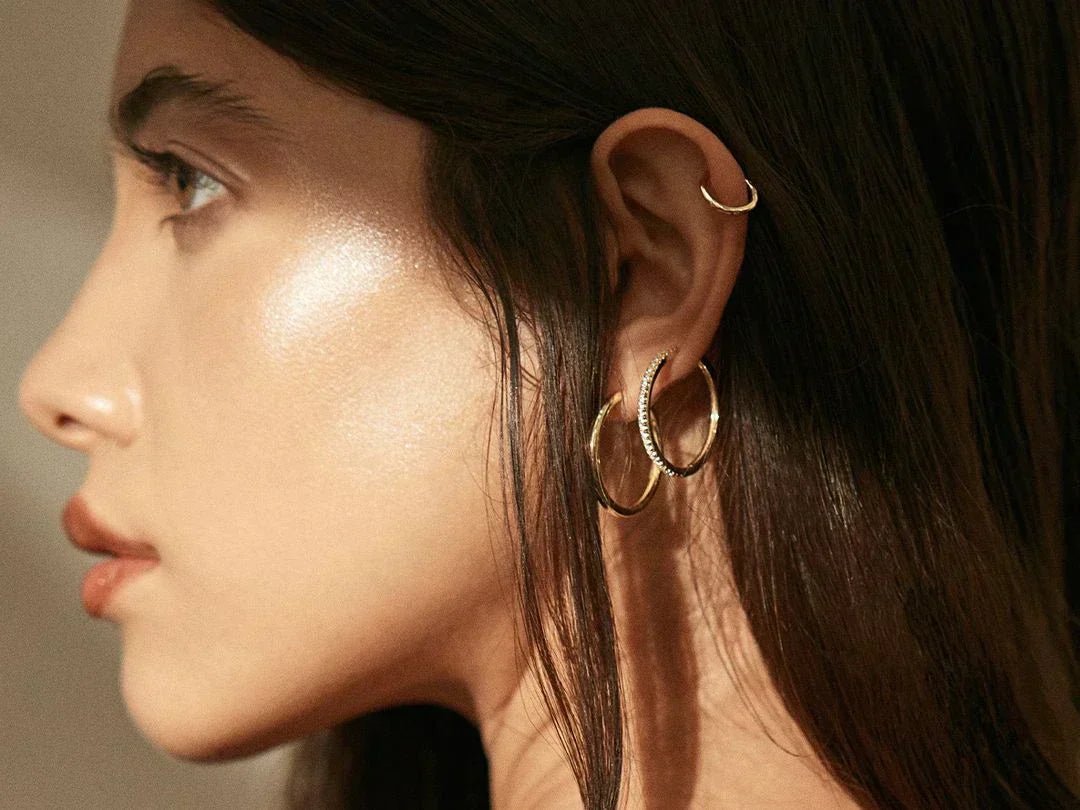 Woman’s ear with multiple gold hoop earrings in the Earrings collection