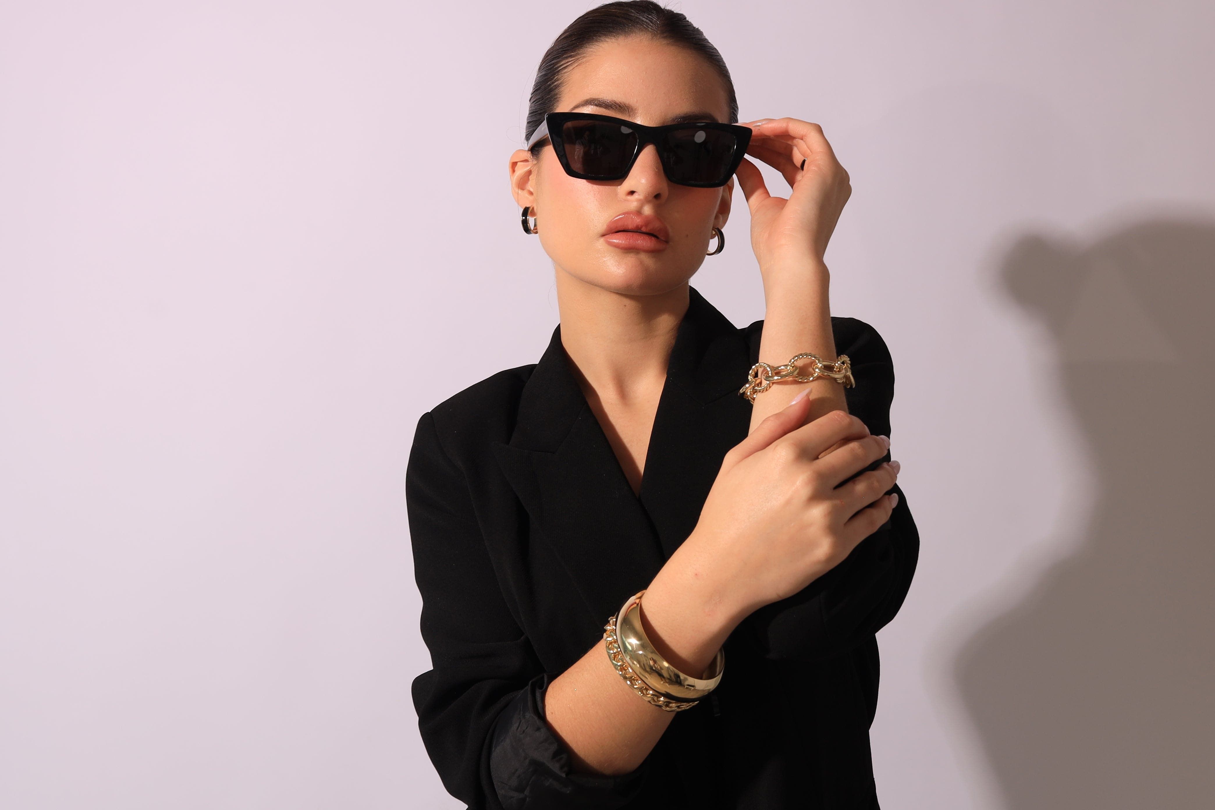 Stylish woman wearing 3/4 inch enamel hoops with a black blazer and sunglasses