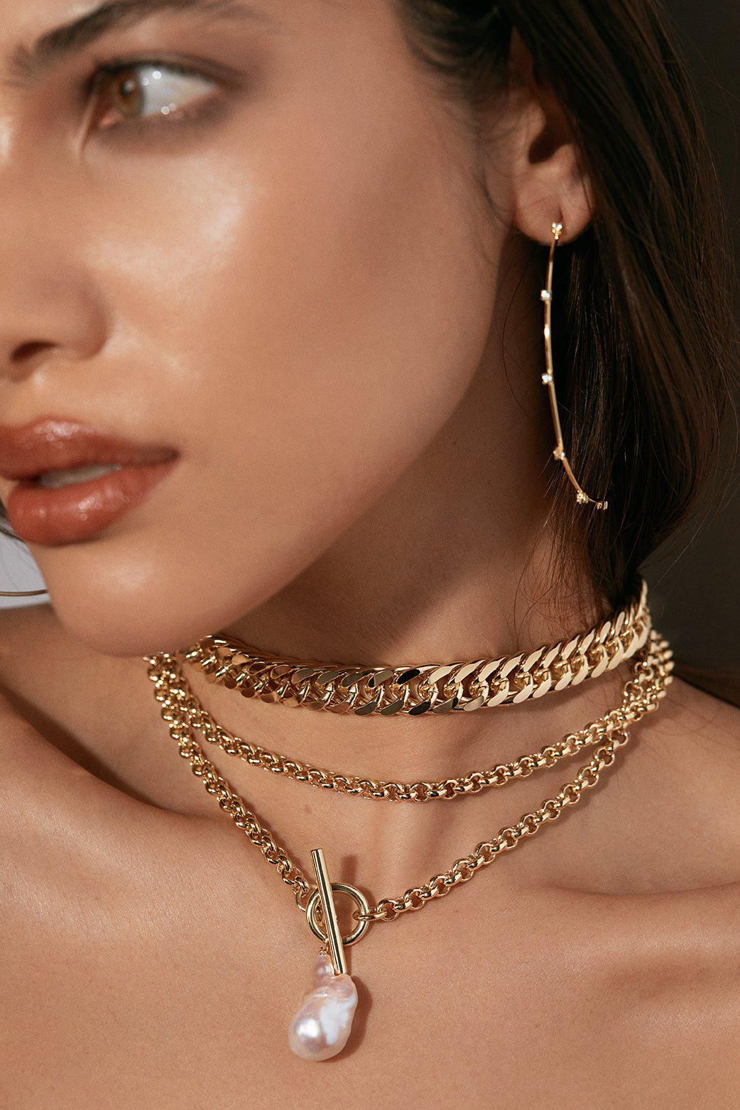 Woman wearing gold jewelry showcasing the Arya Necklace accessory