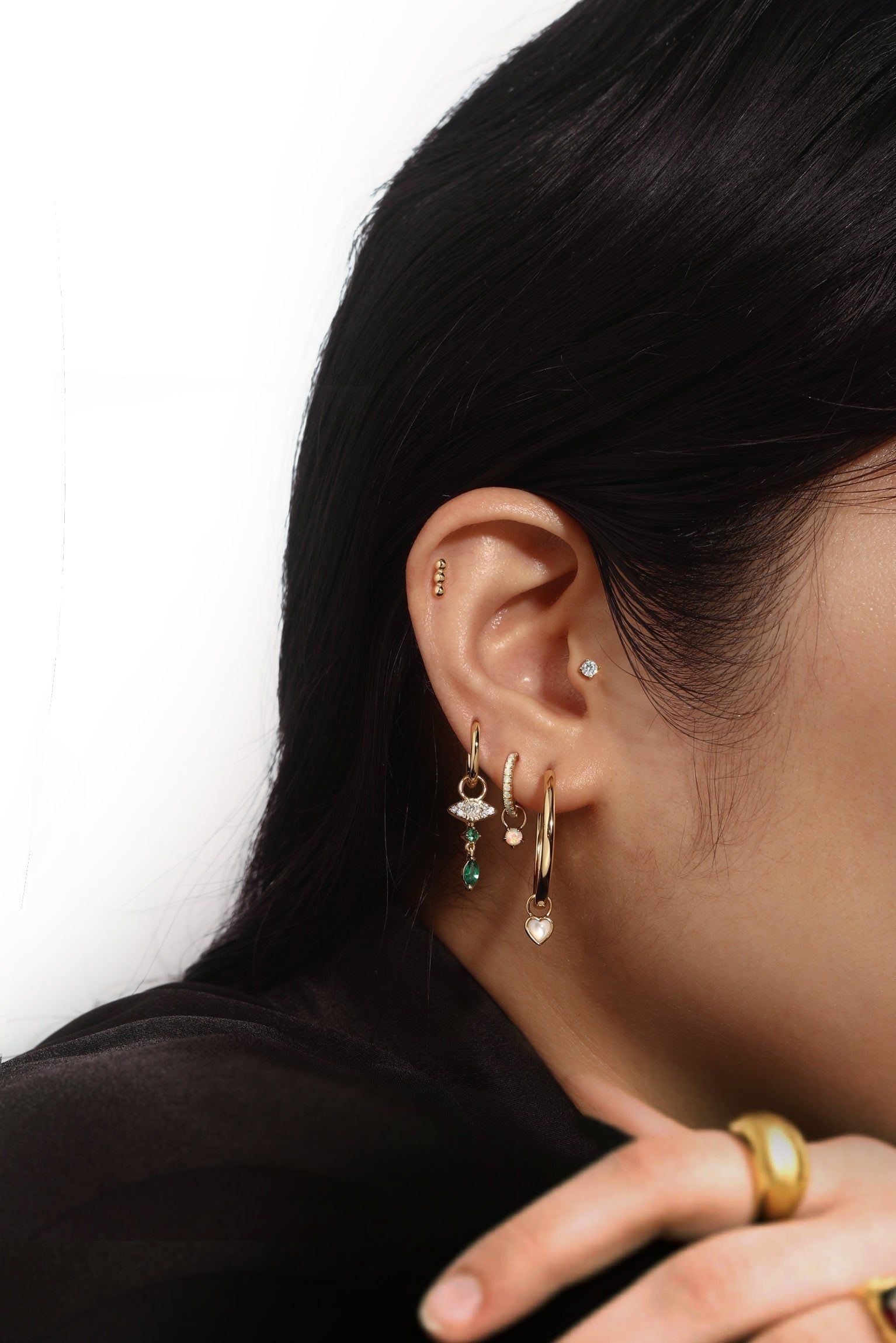 Ear with multiple gold earrings wearing CZ Drip Hoop Charm jewelry