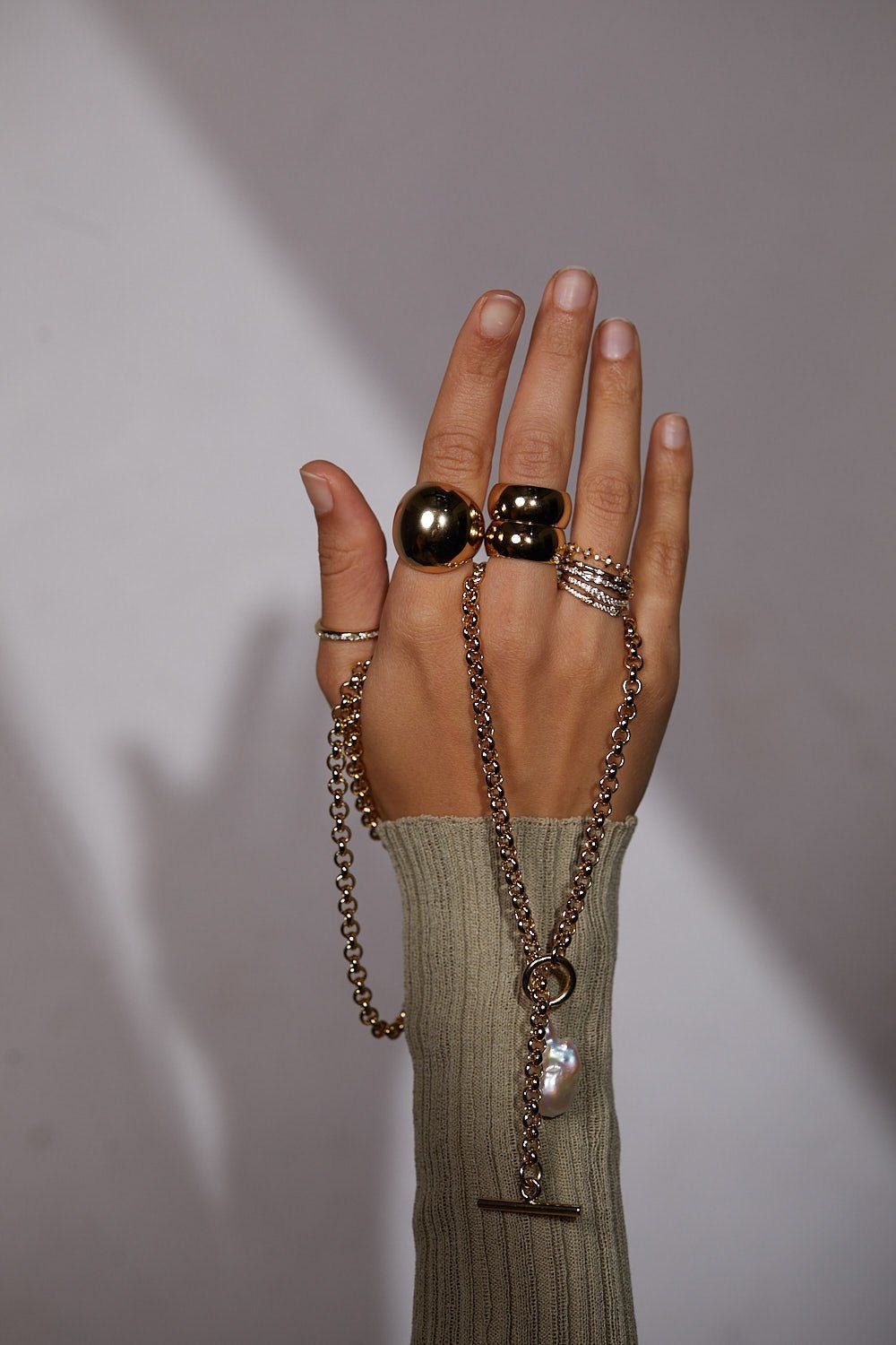 Hand with gold rings and chain necklace wearing CZ Studded Thin Ring jewelry
