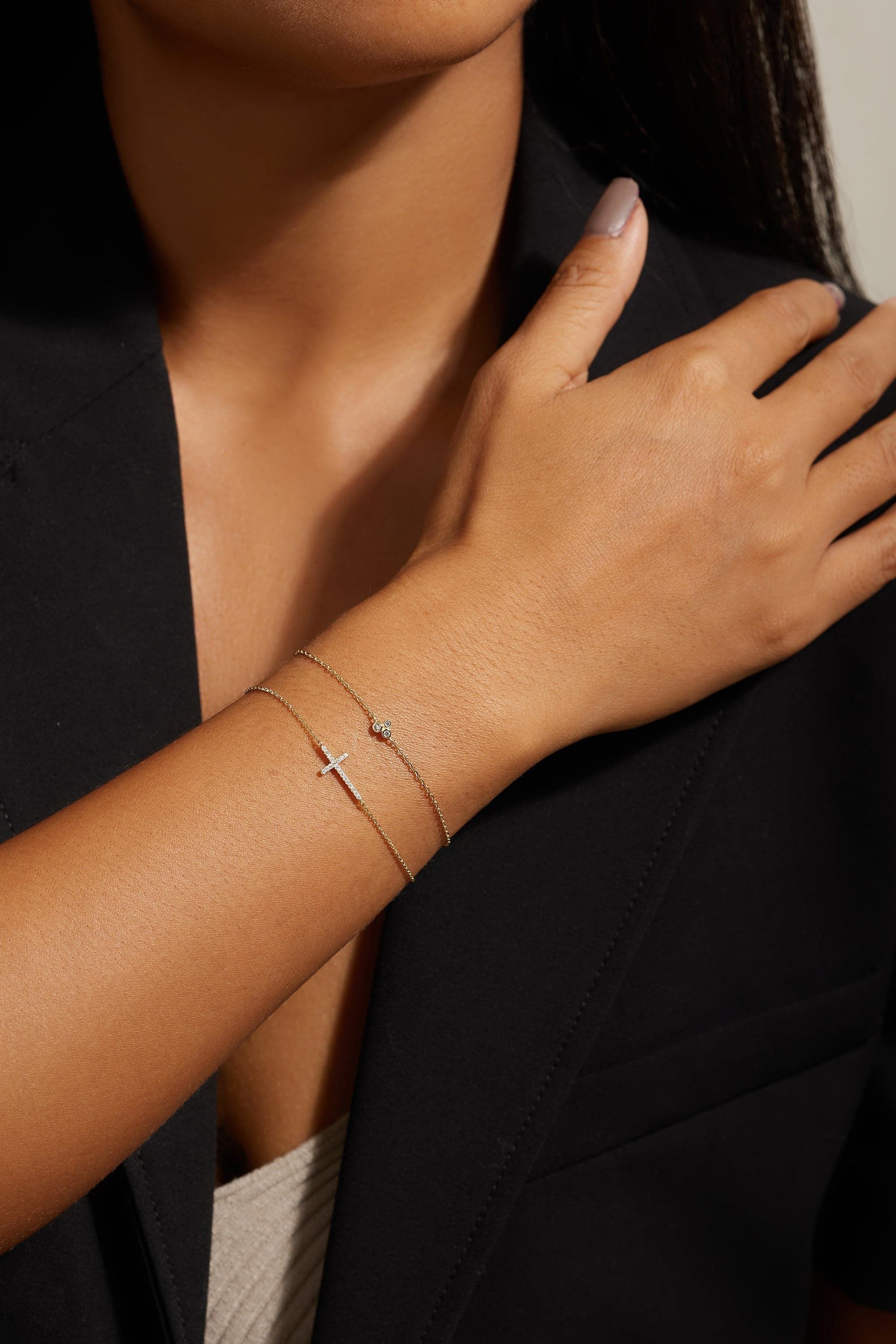Woman’s arm with delicate gold bracelets showcasing the Horizontal CZ Cross Bracelet