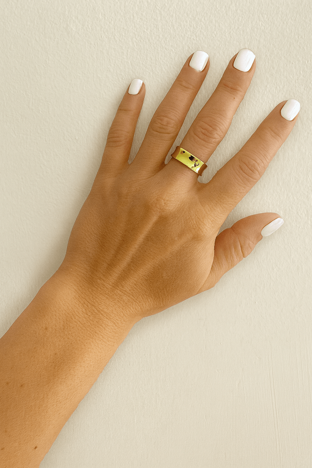 Woman’s hand with white nail polish wearing a Wide Gold Small Olivia Ring