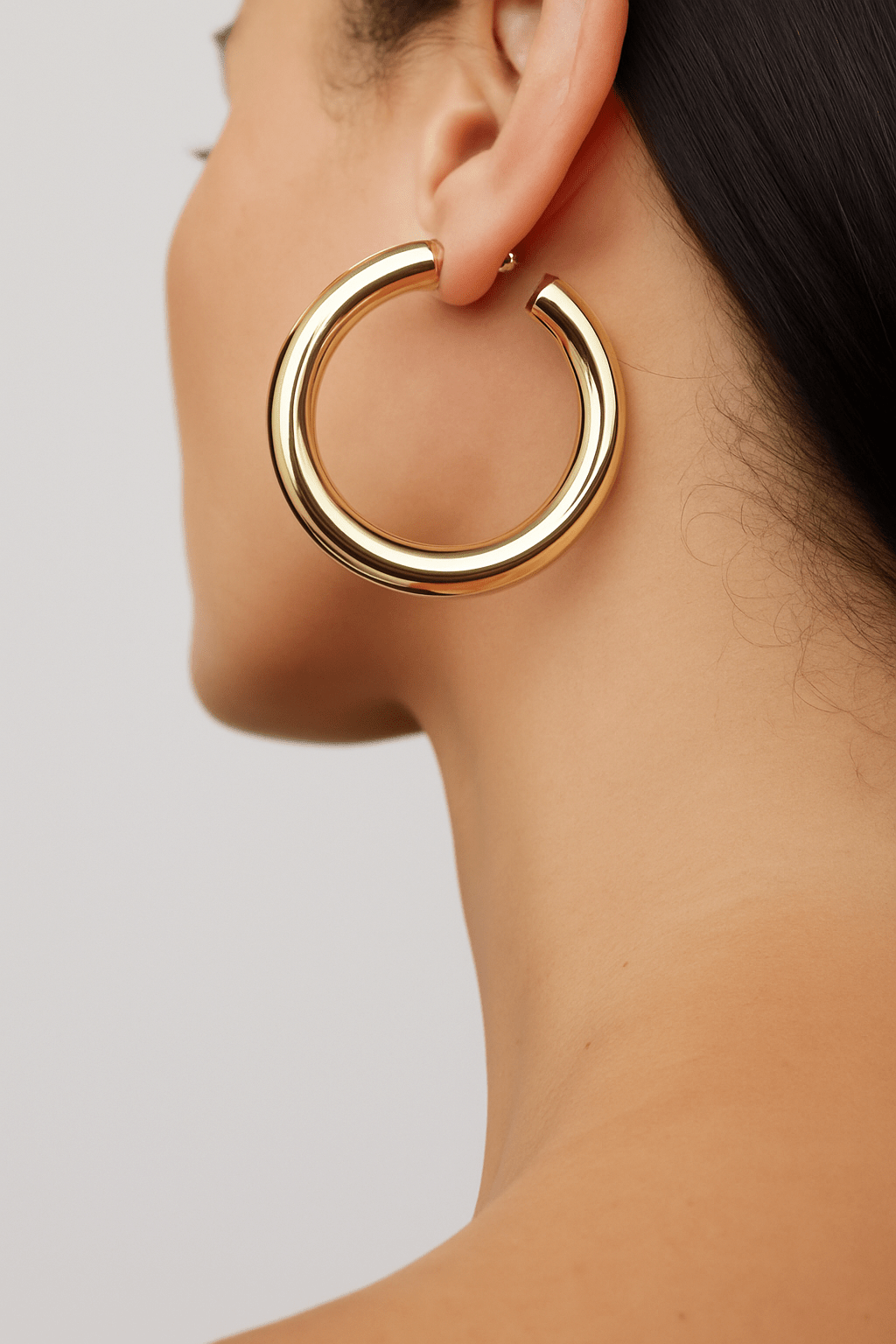 Thick gold hoop earring on a person’s ear from 1.5 Kelly Hoops collection
