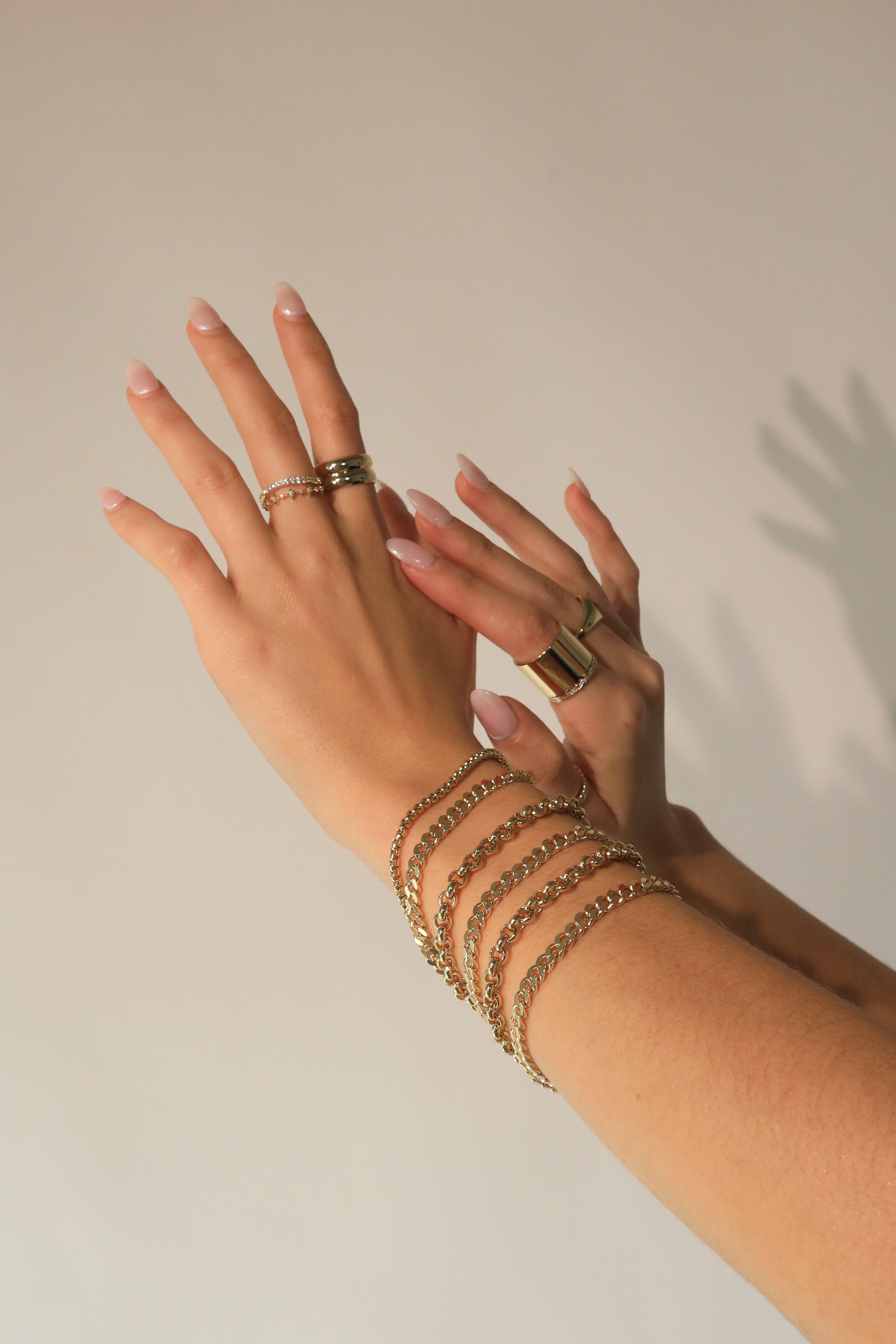 Hands with gold jewelry showing off the Micro Link Curb Chain Bracelet in style