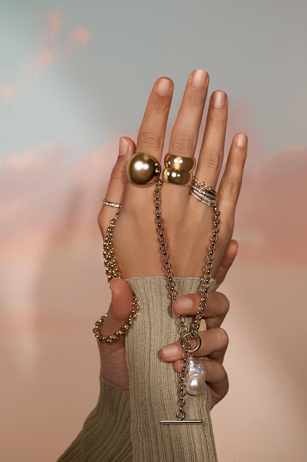 Close-up of hands with gold rings and a pearl necklace for Twinkle CZ Ring product
