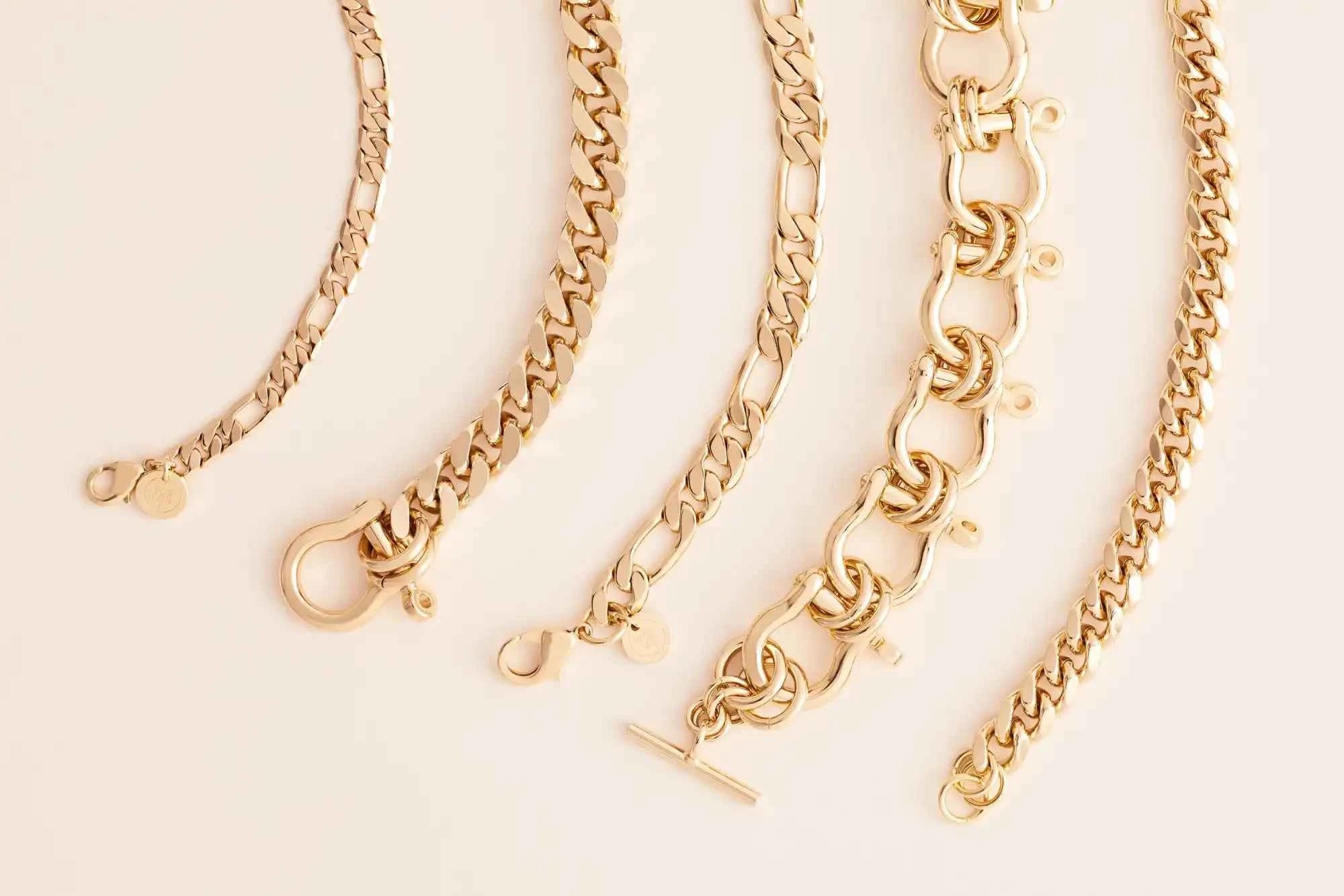 Gold chain necklaces on a light beige background