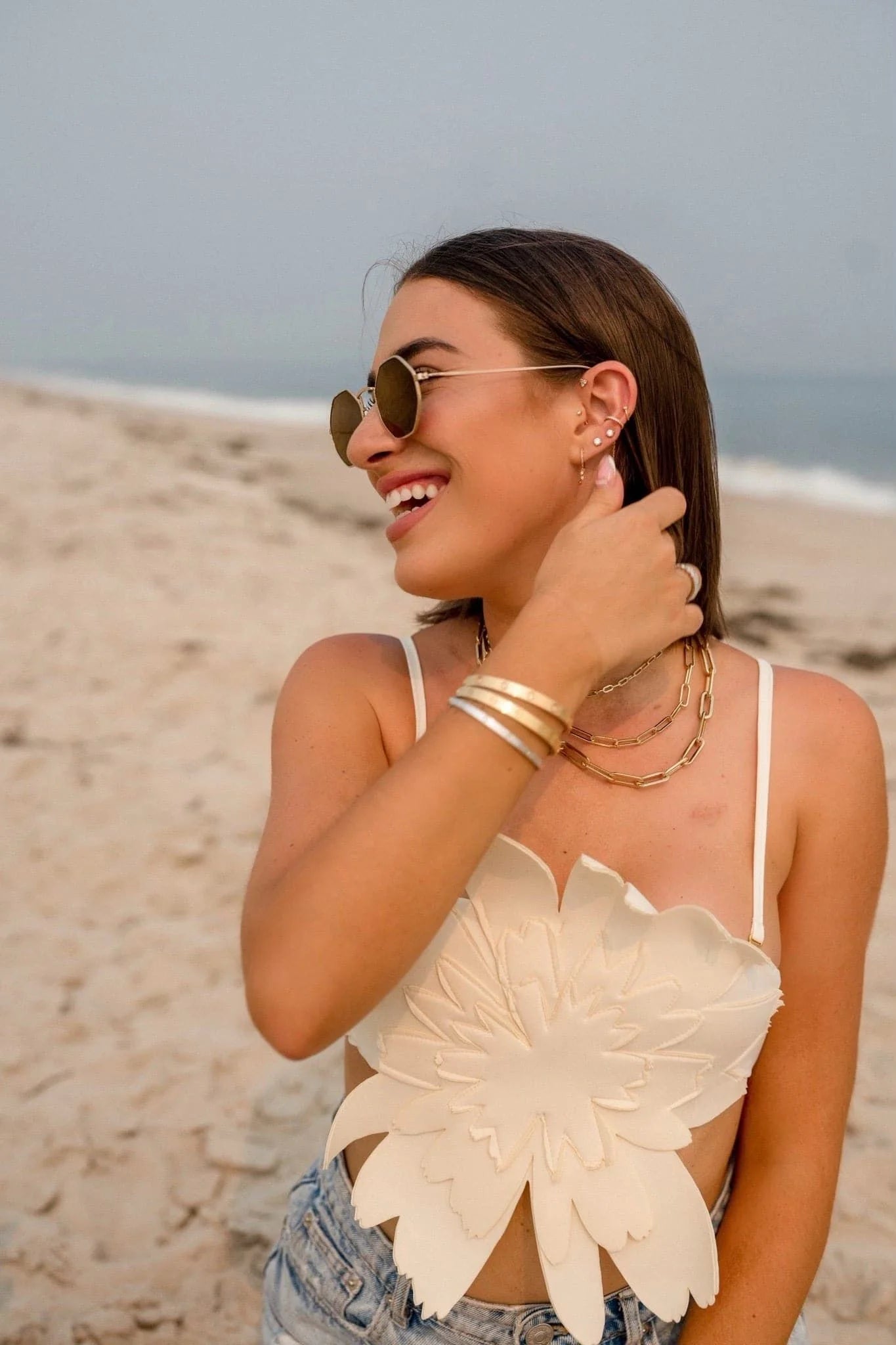 Smiling woman in a floral top wearing Dr. Bridget Necklace, brass plated 14k gold jewelry