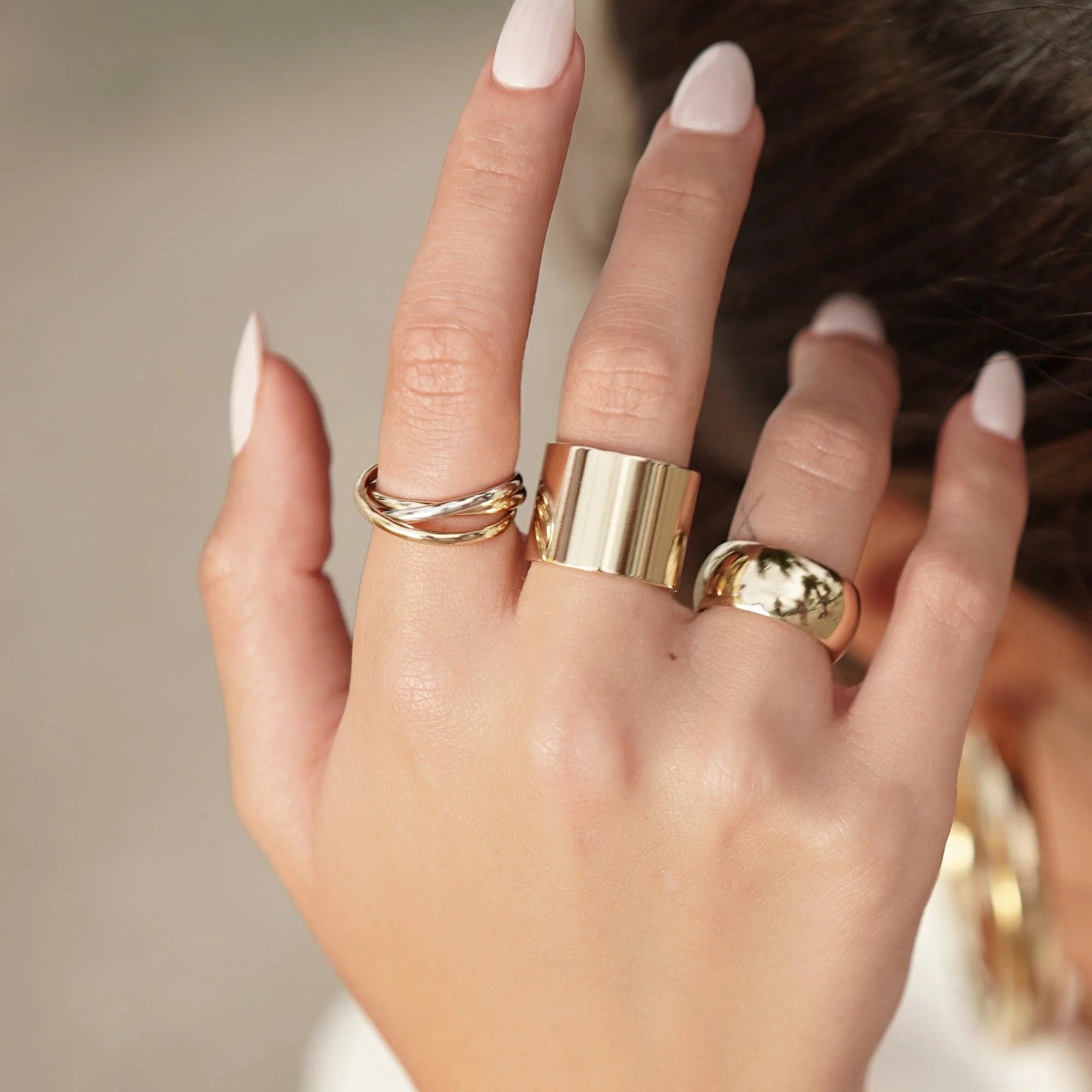 Hand with thick flat ring in recycled brass plating, a statement piece with clear protective coating