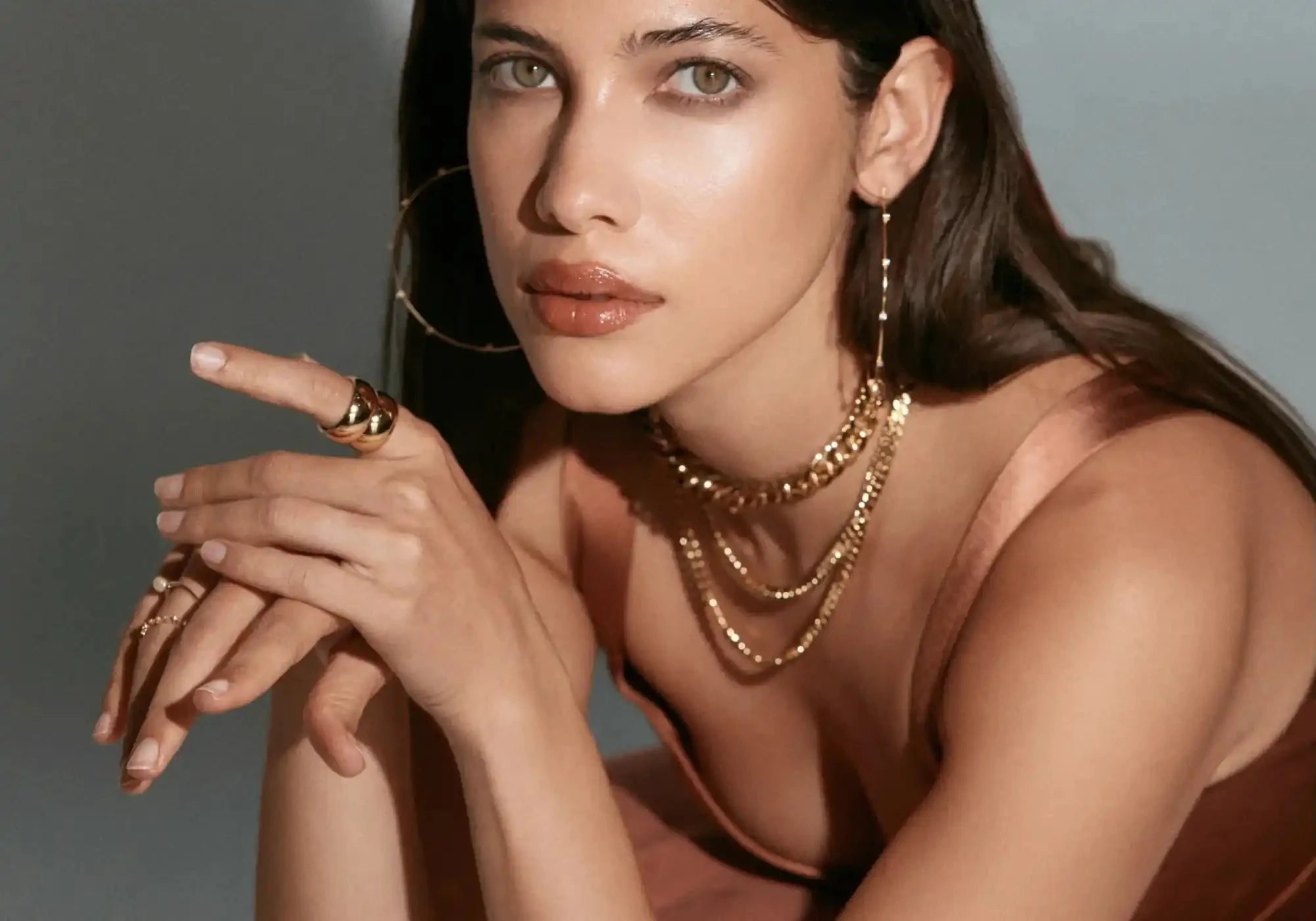 Woman wearing gold jewelry against a neutral background