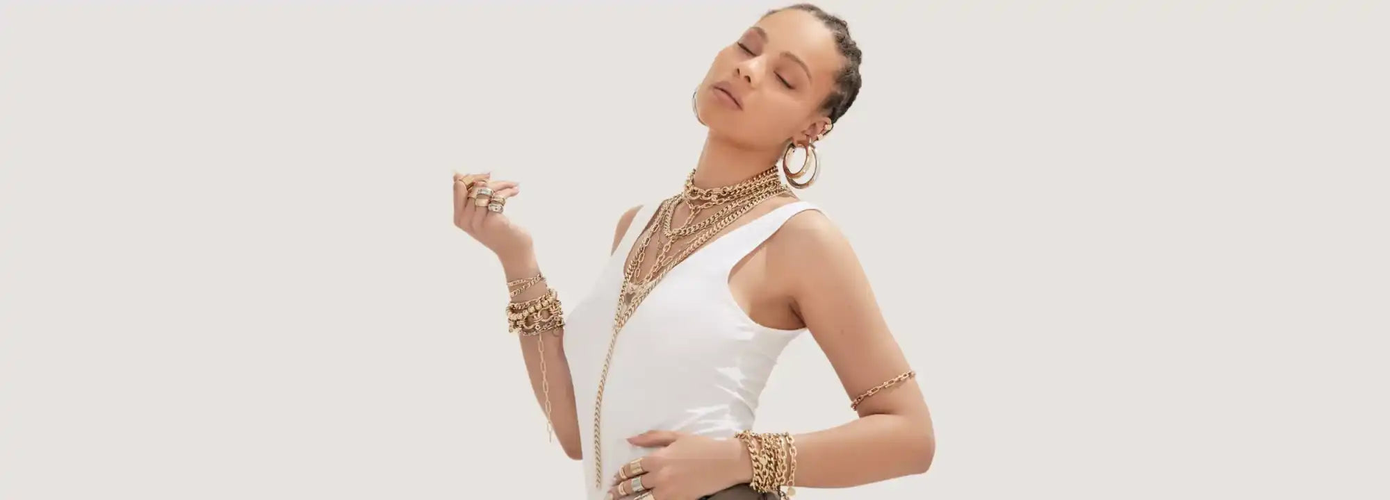 Woman in white sleeveless top and gold jewelry.