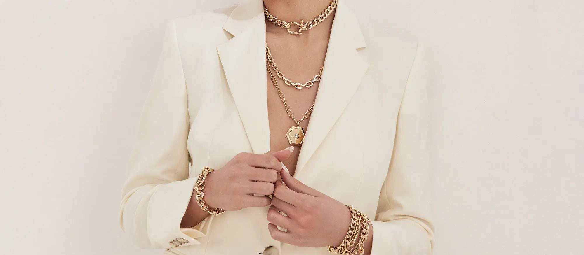 Woman wearing gold jewelry and a white blazer in CHARM NECKLACES collection
