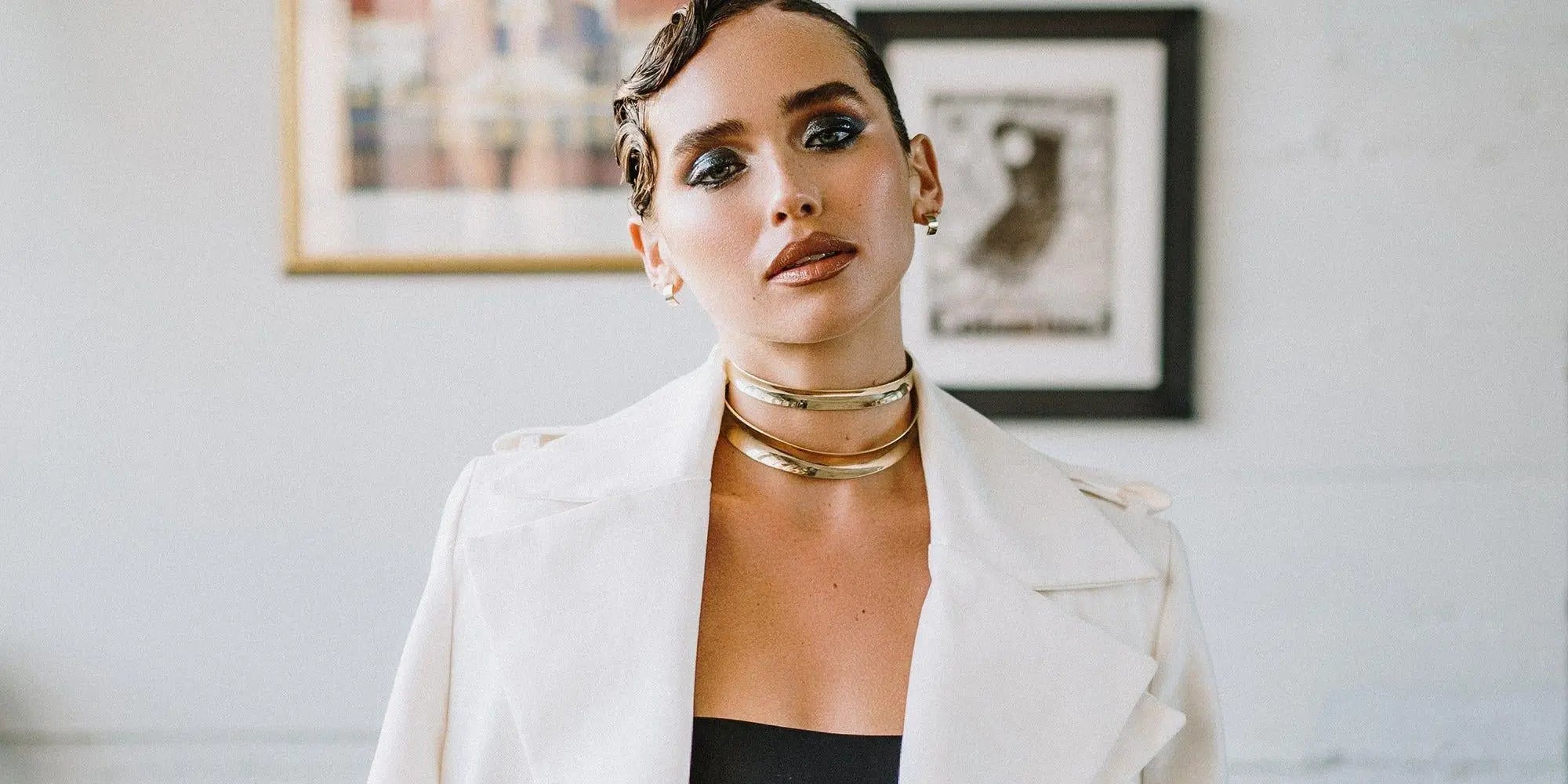 Woman wearing a white jacket and gold necklaces in the Chokers & Collars collection