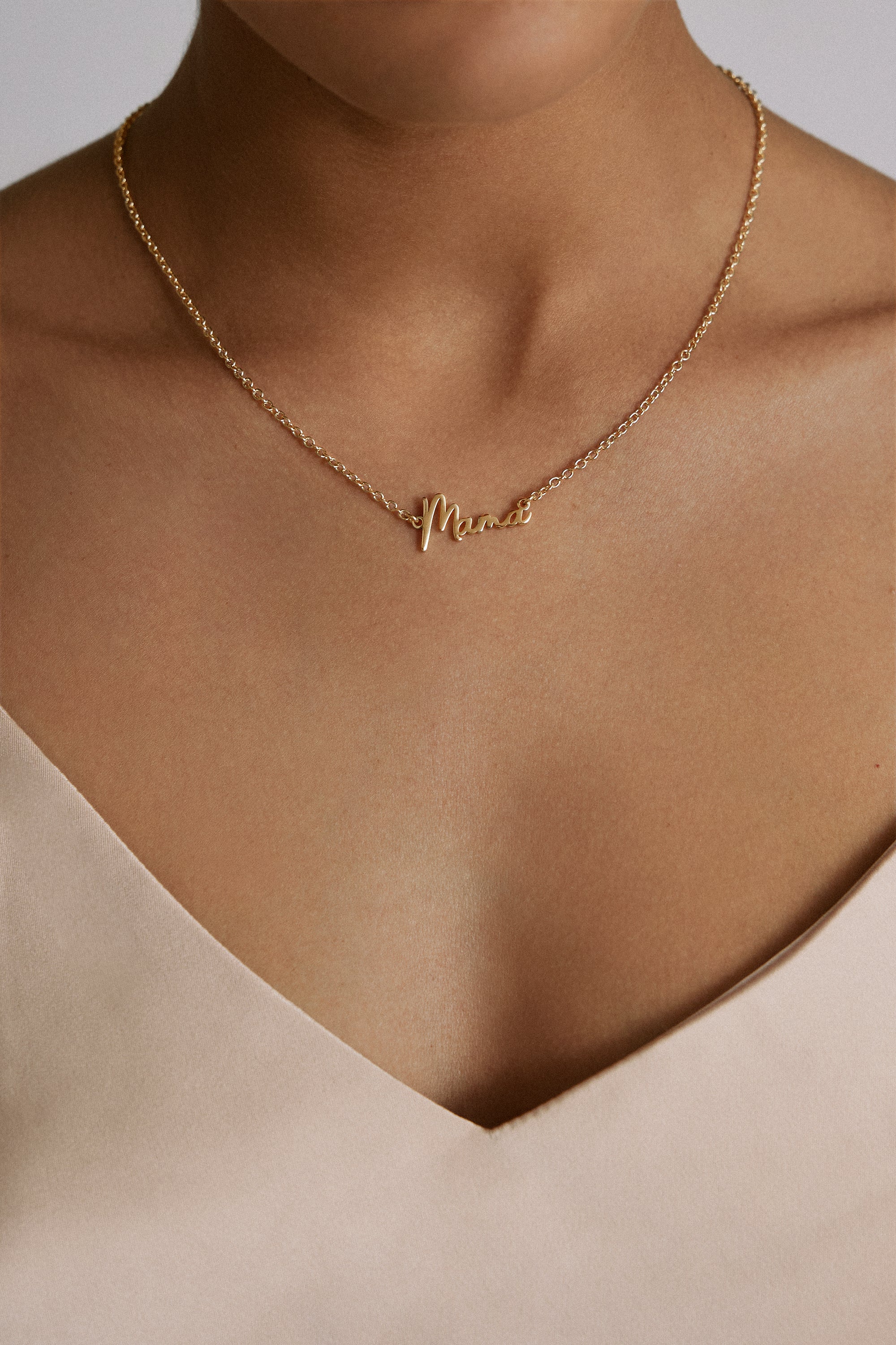 Gold-colored cursive Mama necklace worn on woman’s neck, elegant Dainty Script Mama Jewelry