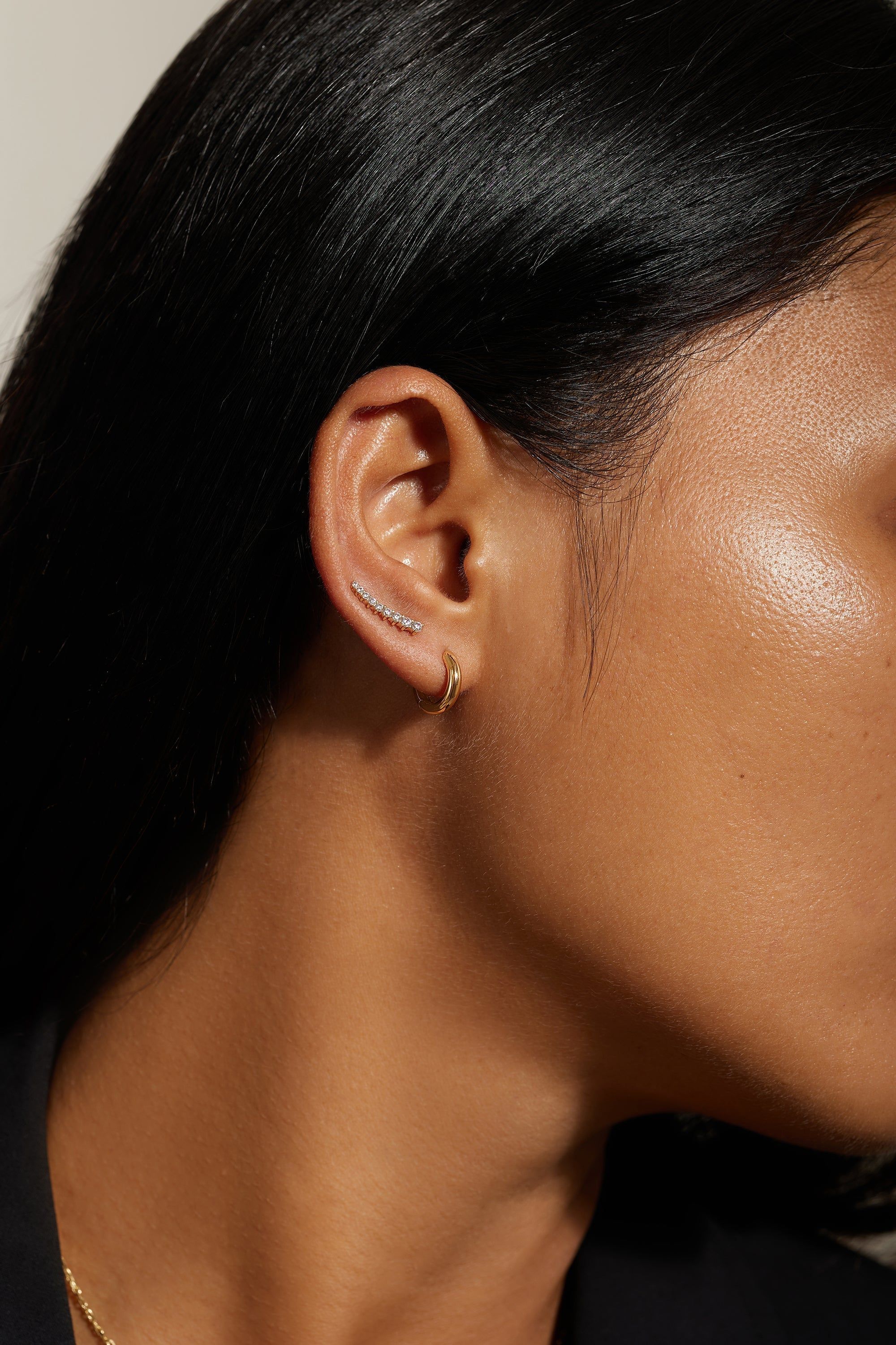 Ear with two gold earrings wearing the Graduated CZ Bar Ear Crawl jewelry accessory
