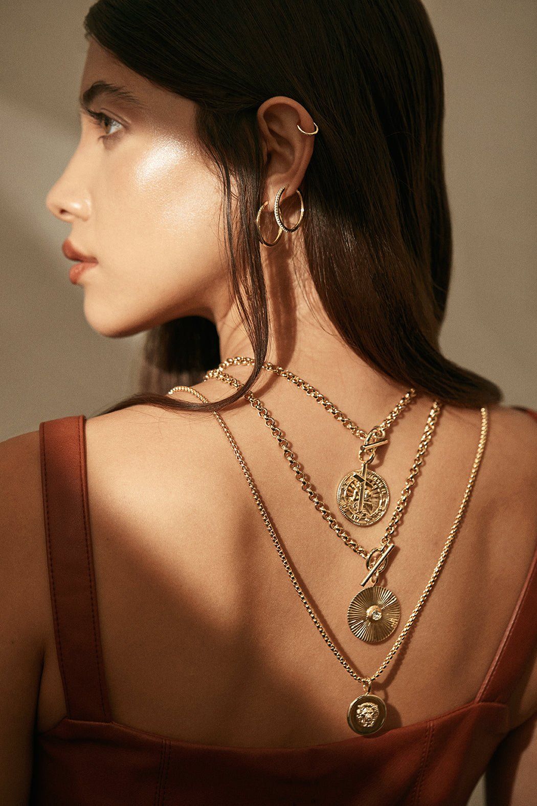 Woman showing off Micro Royal Toggle and Ocean Pendant Necklace in gold jewelry style