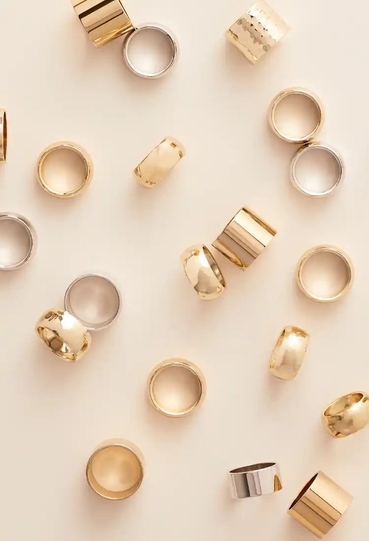 A collection of gold and silver-colored wide band rings.