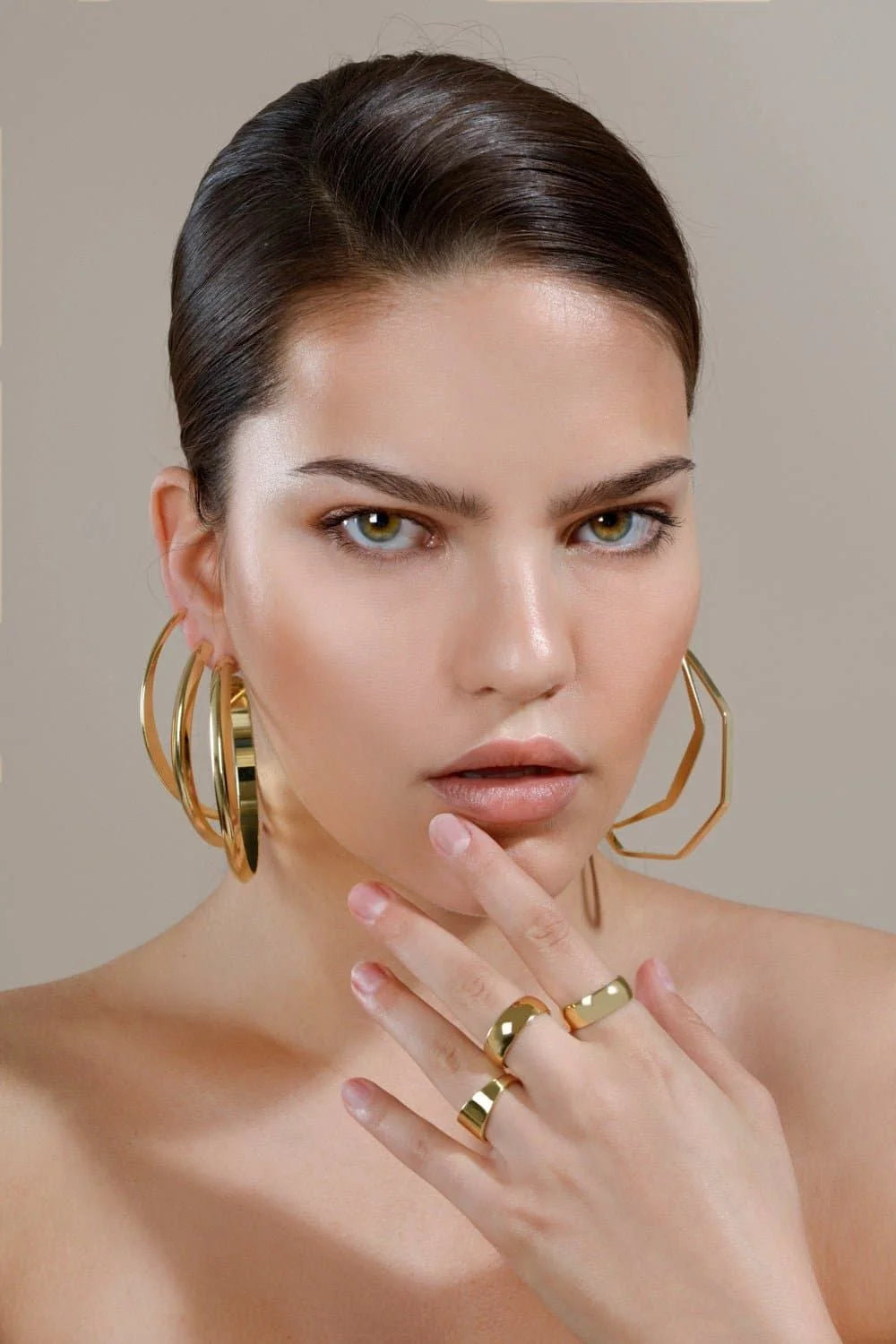 Woman wearing Jerry Hoops octagon shaped hoop jewelry with inch wide brass finish