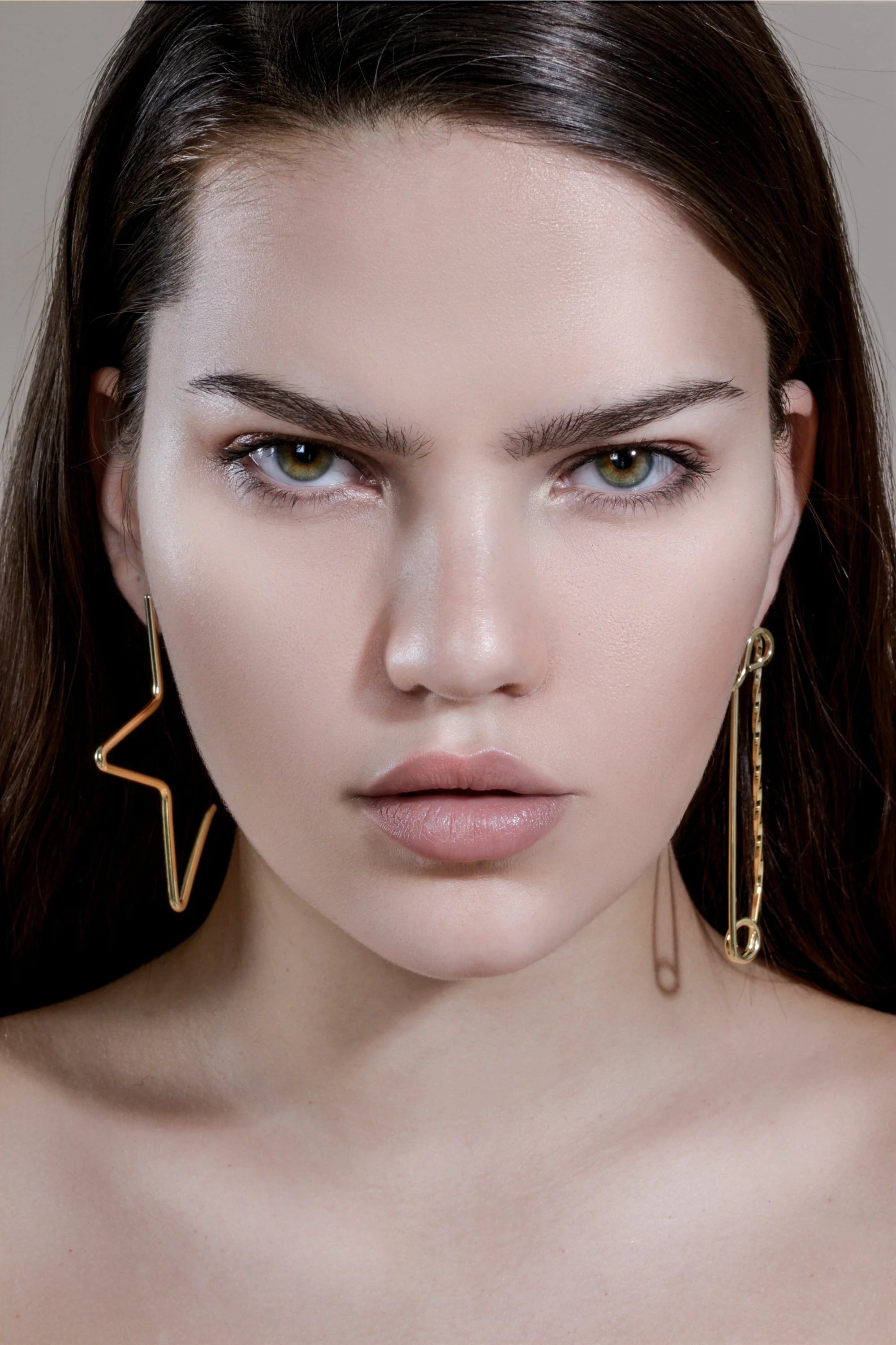 Stern-faced woman wearing large 1/2 star earrings in 14k yellow gold rhodium finish