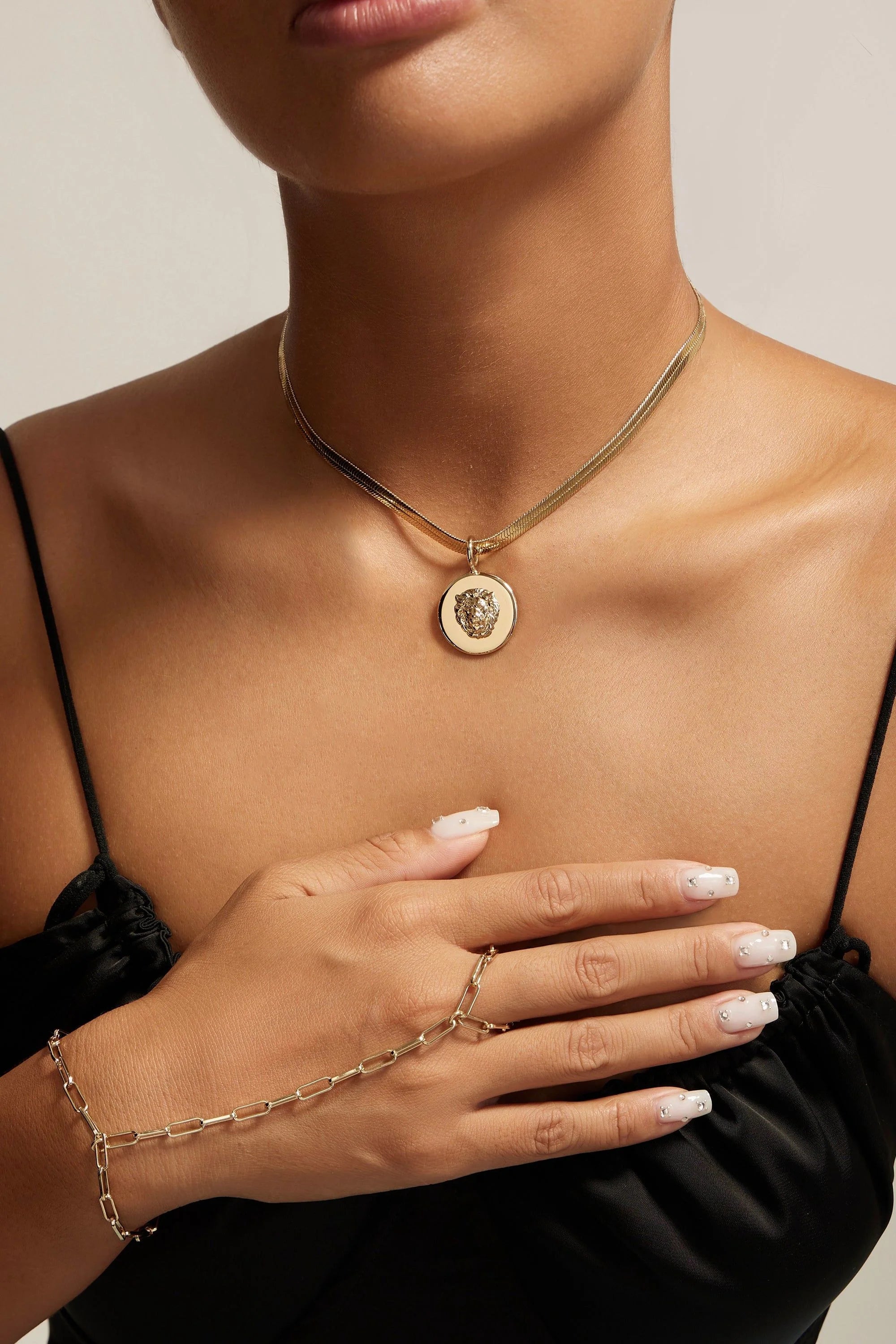 Gold necklace with hand chain featuring Leni Lion Pendant and Lion Head Pendant in recycled brass