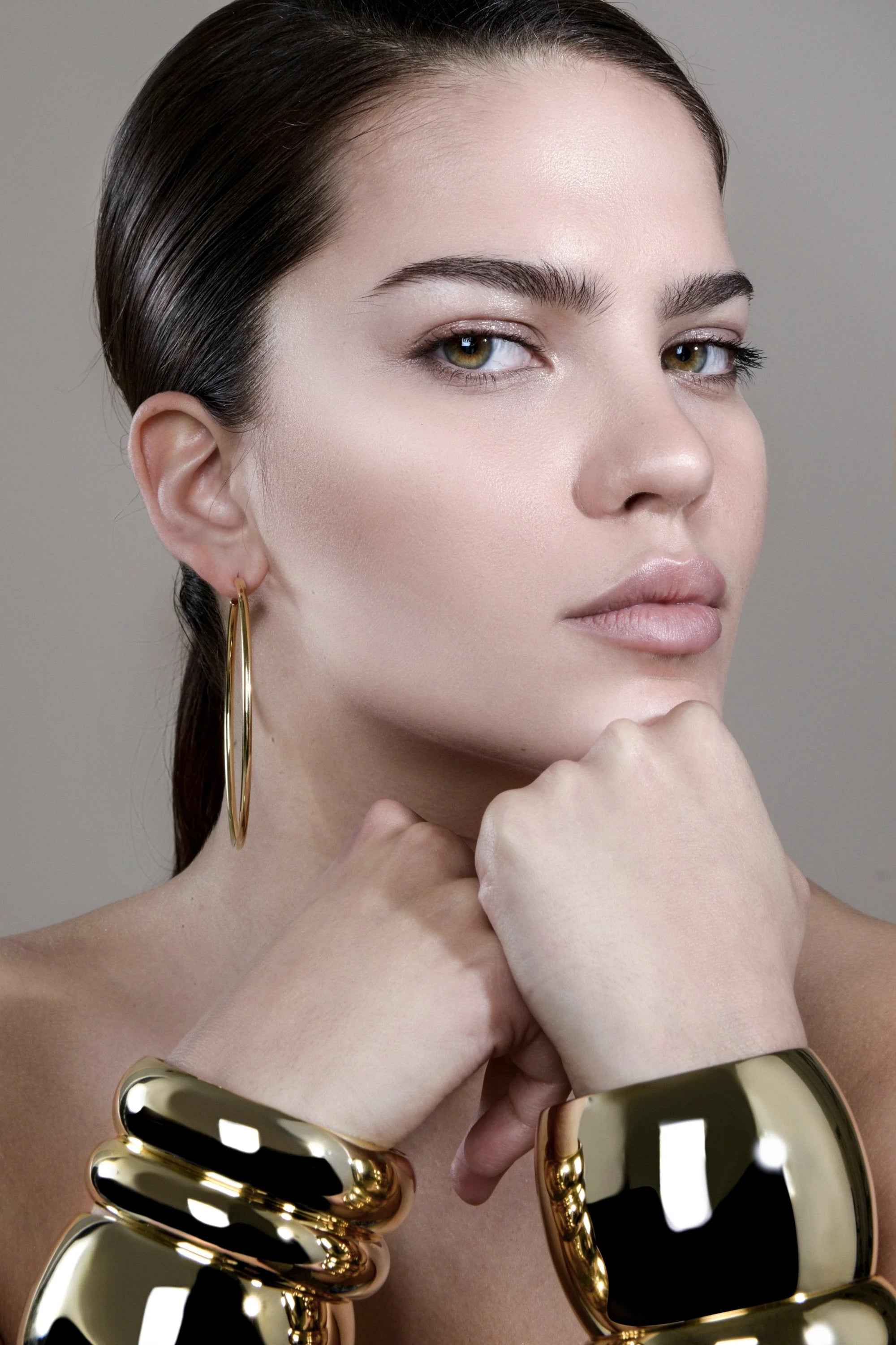 Woman wearing a Medium Athena Bangle made of recycled brass with inch wide domed design