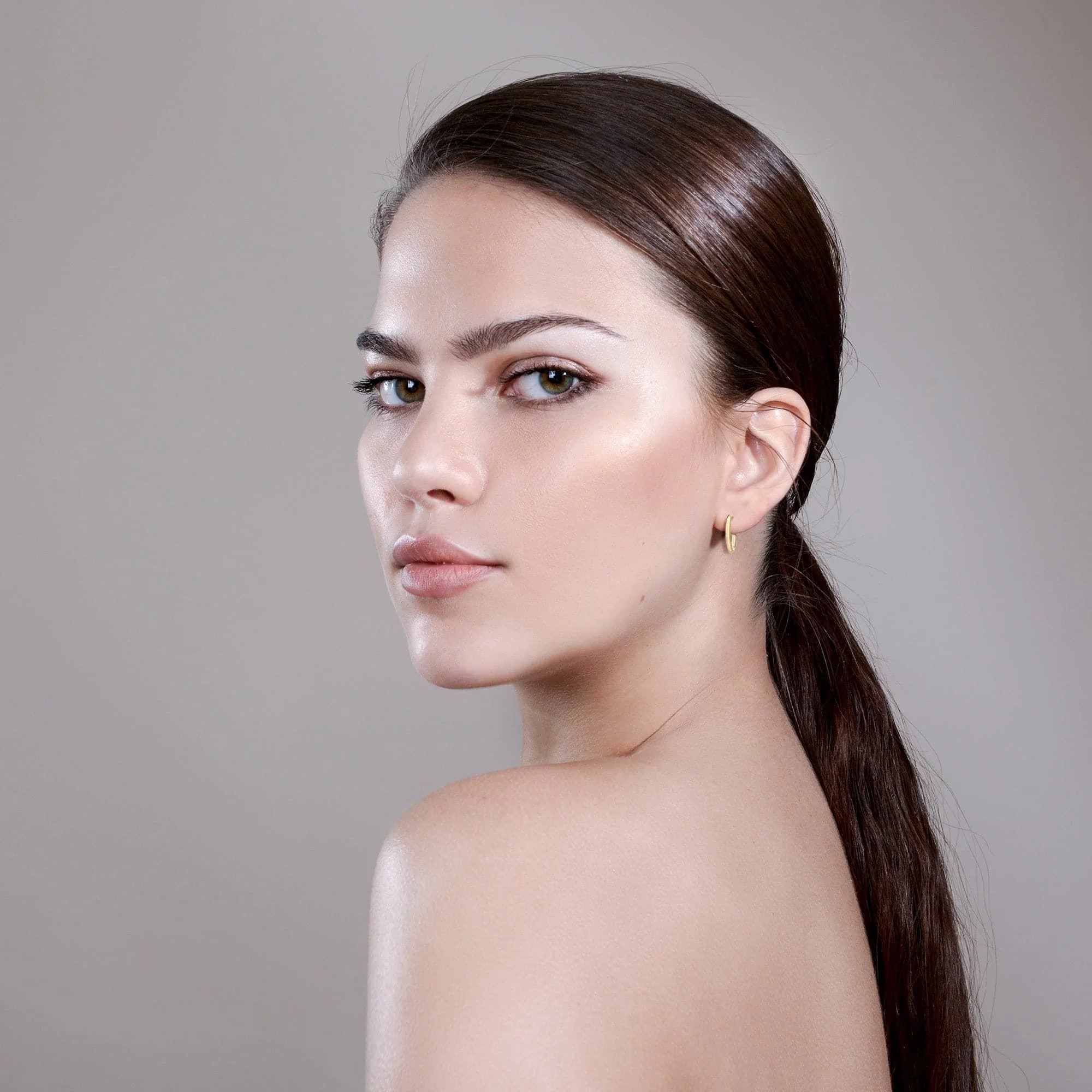 Woman with glowing skin wearing Mini .5 Ultimate Hoops brass wire hoop in recycled brass wire