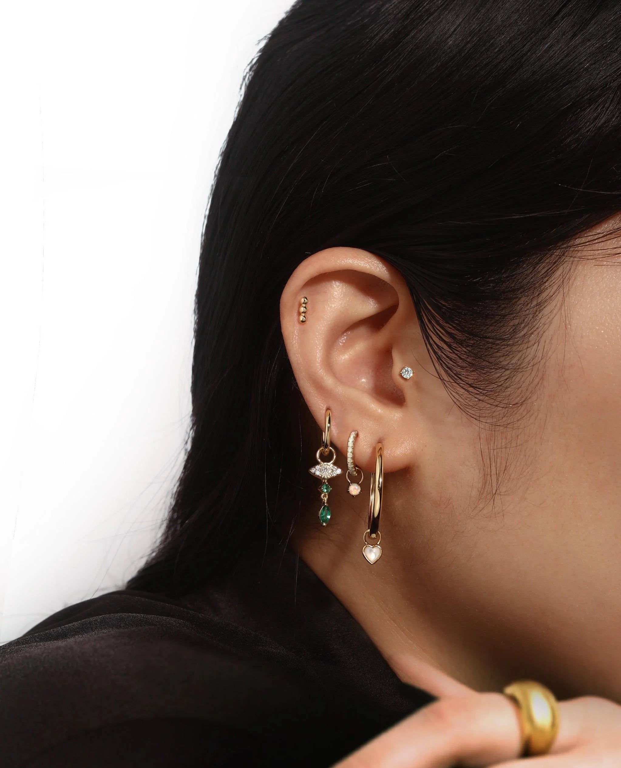 Ear with multiple gold earrings from Mother Of Pearl Heart Hoop Charm in demi-fine collection