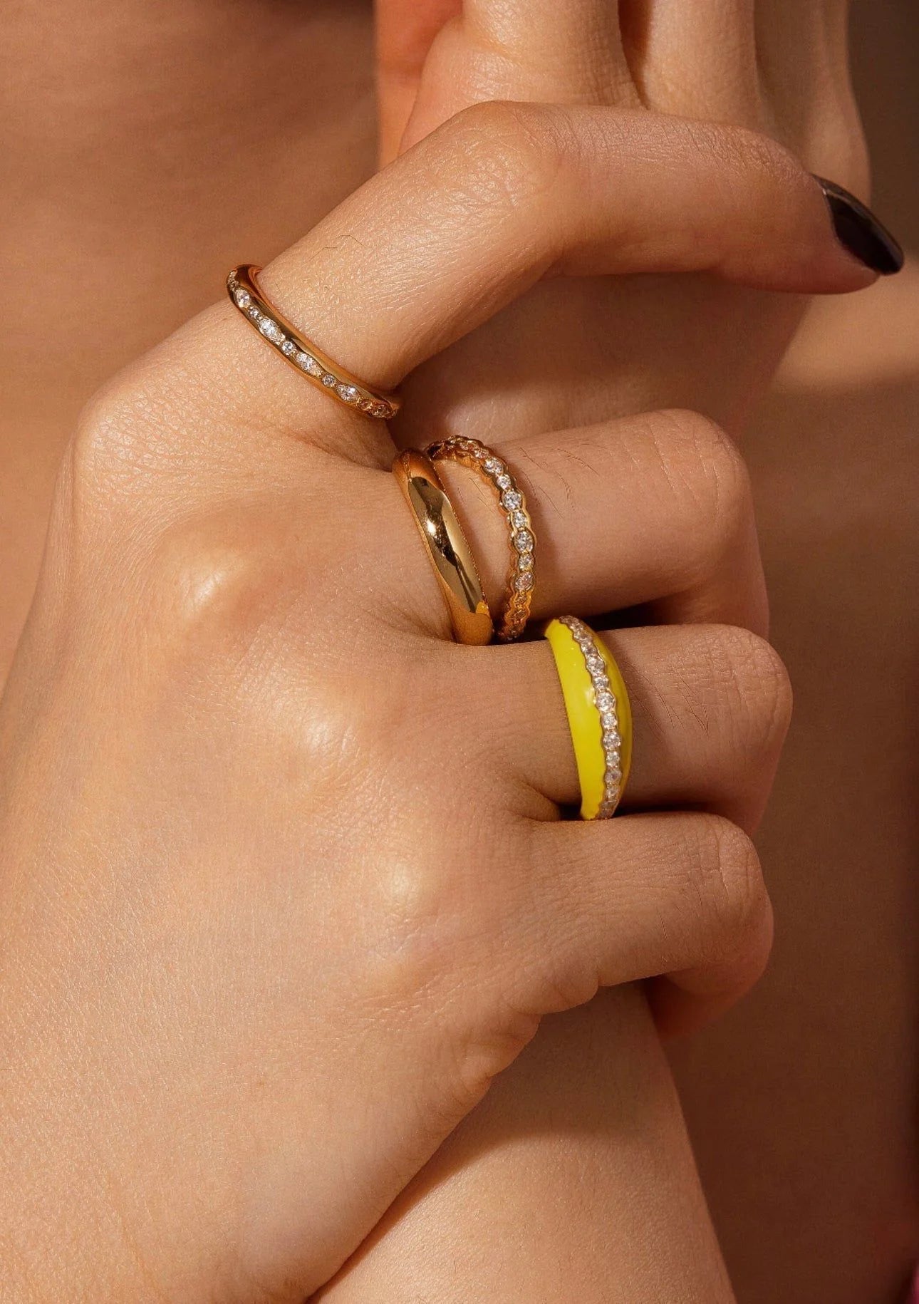 Hand with eklexic’s stunning multi-shaped 14k gold vermeil channel promise rings