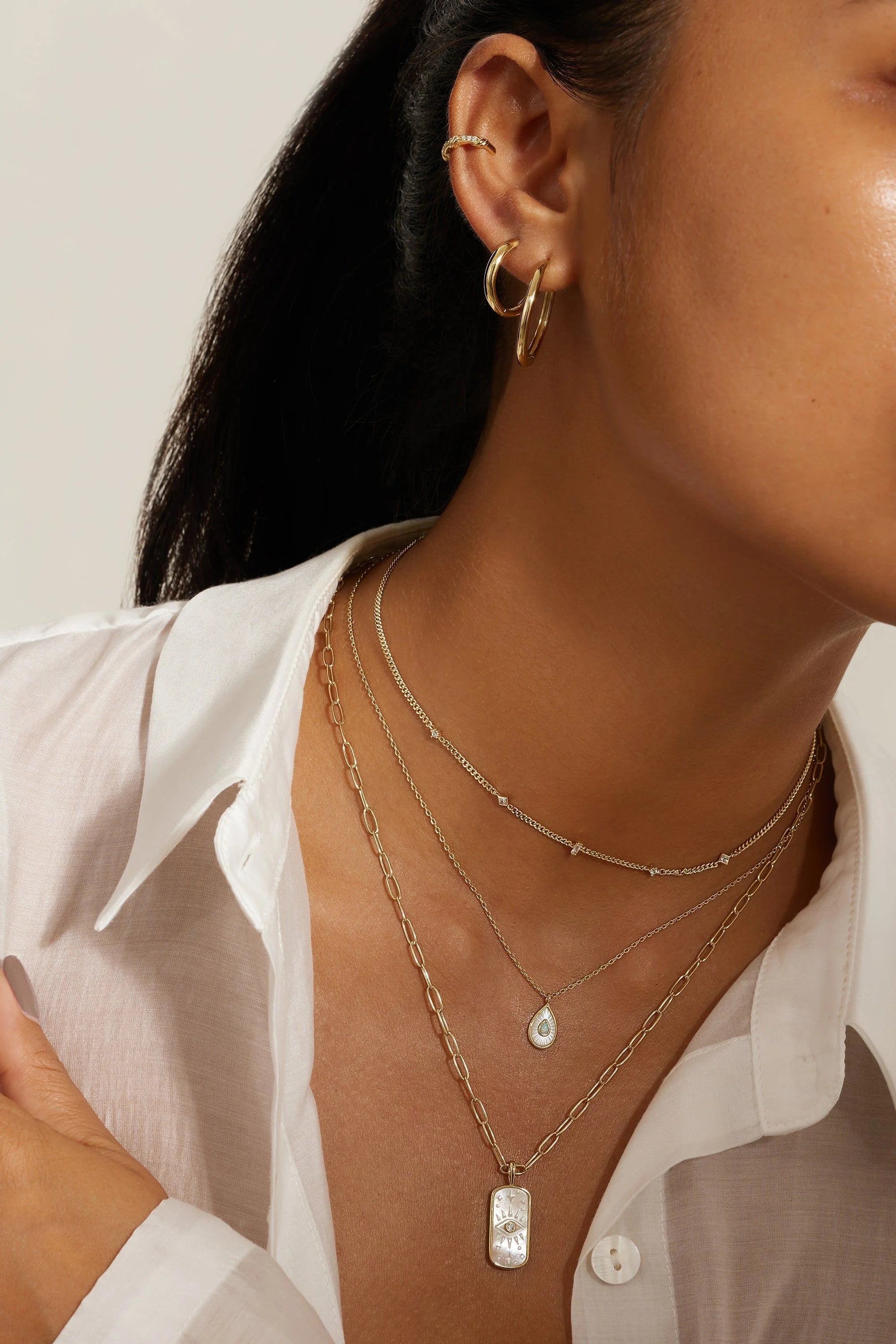 Layered 14k gold necklaces and hoop earrings with pear-shaped Mop pendant and opal