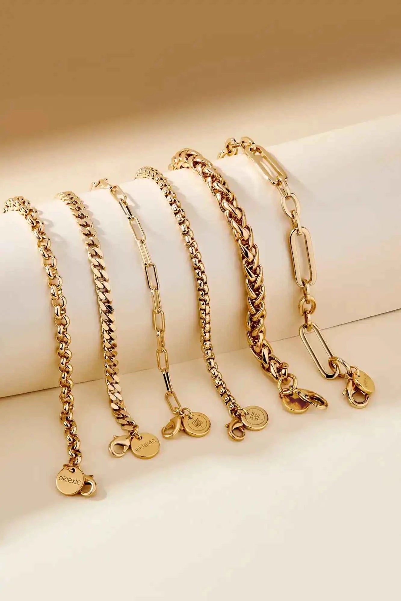 Set of gold chain necklaces on a beige surface