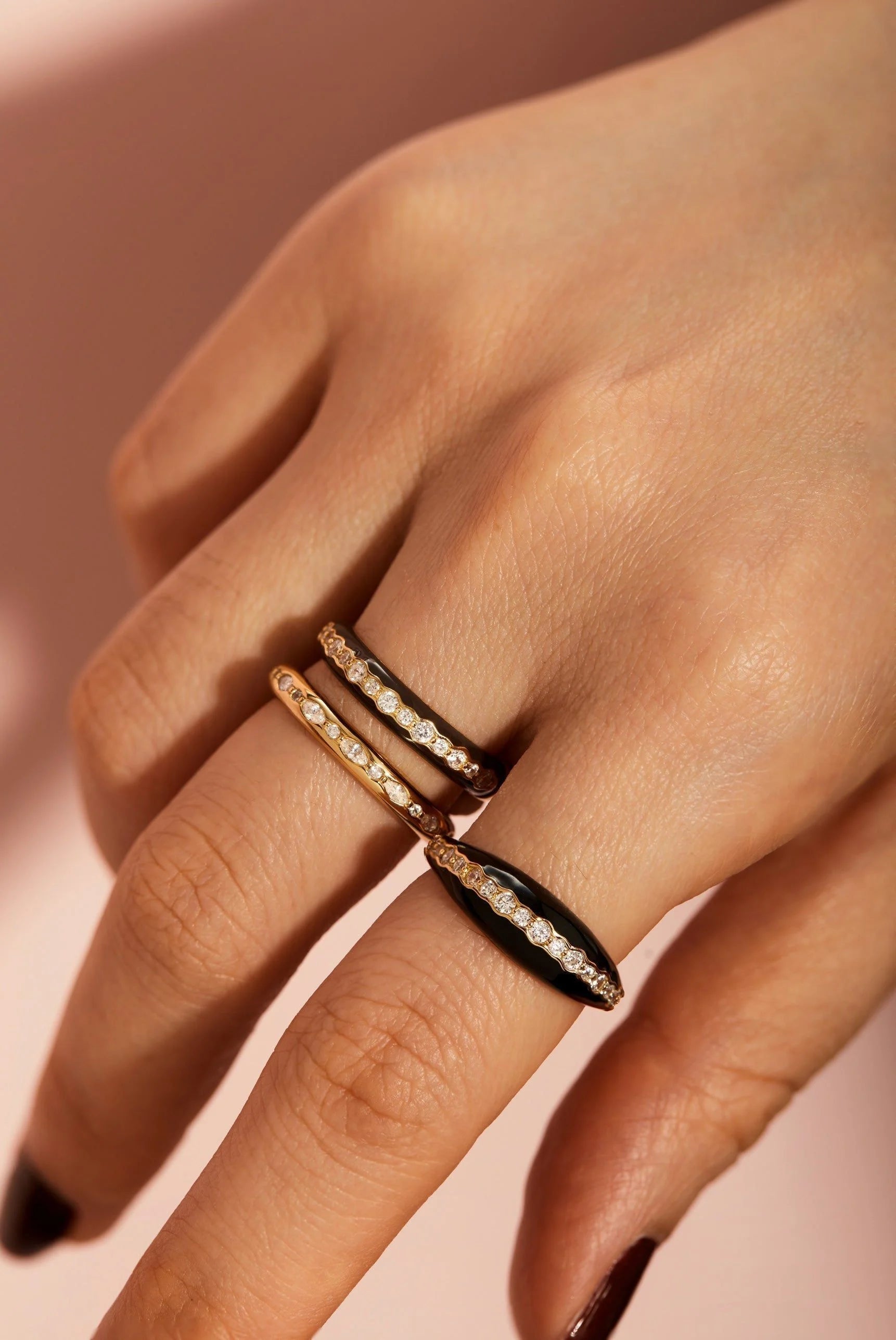 Hand wearing three gold vermeil rings with black enamel and CZ accents on sterling silver