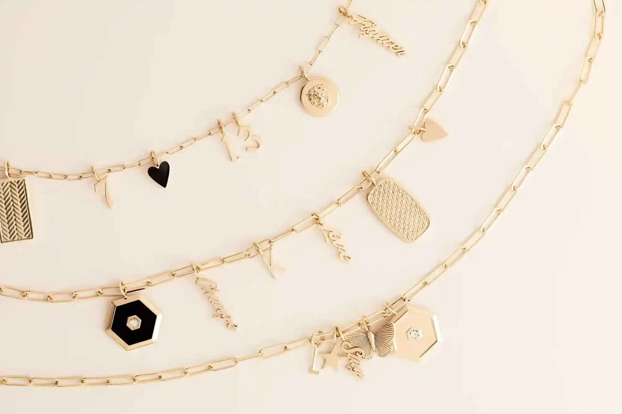Three gold layered necklaces with various charms.