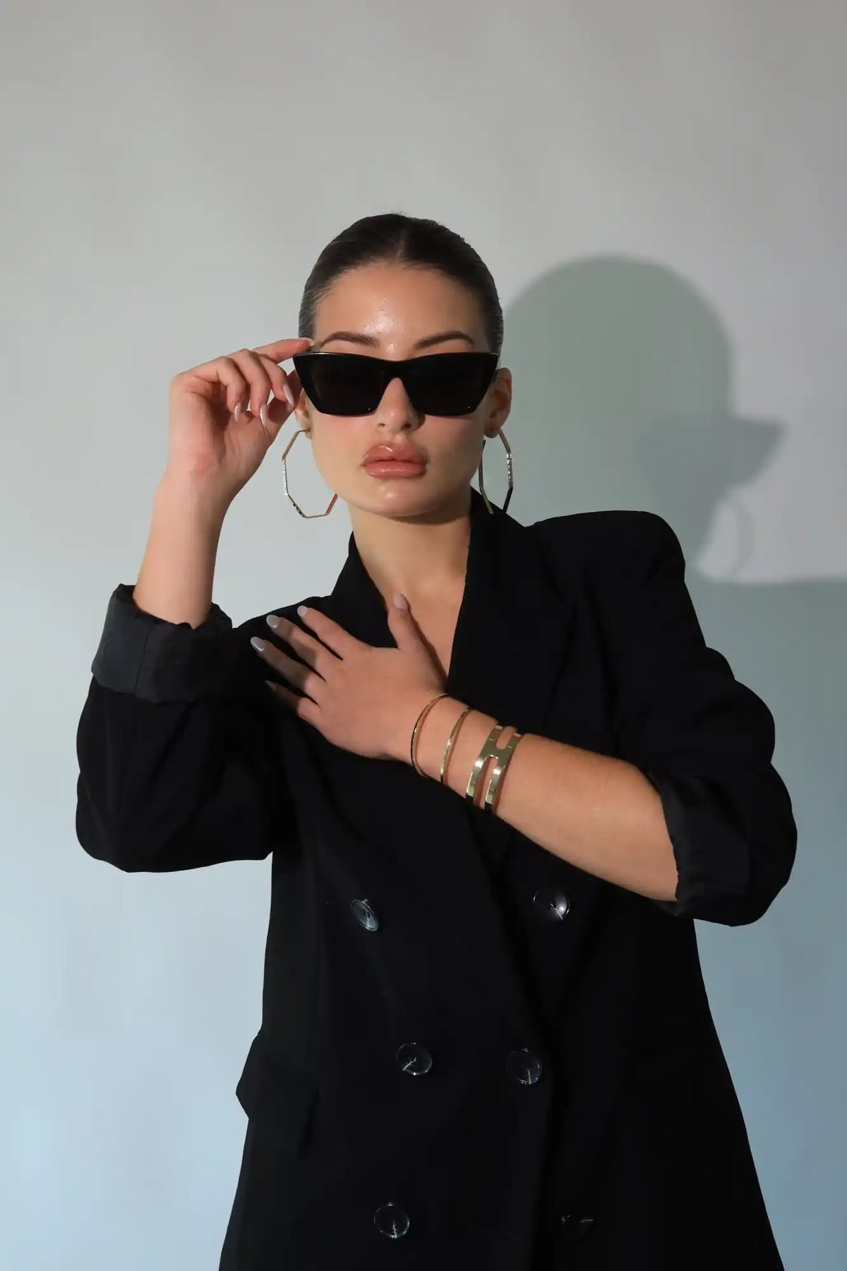 Woman in a black blazer and sunglasses.