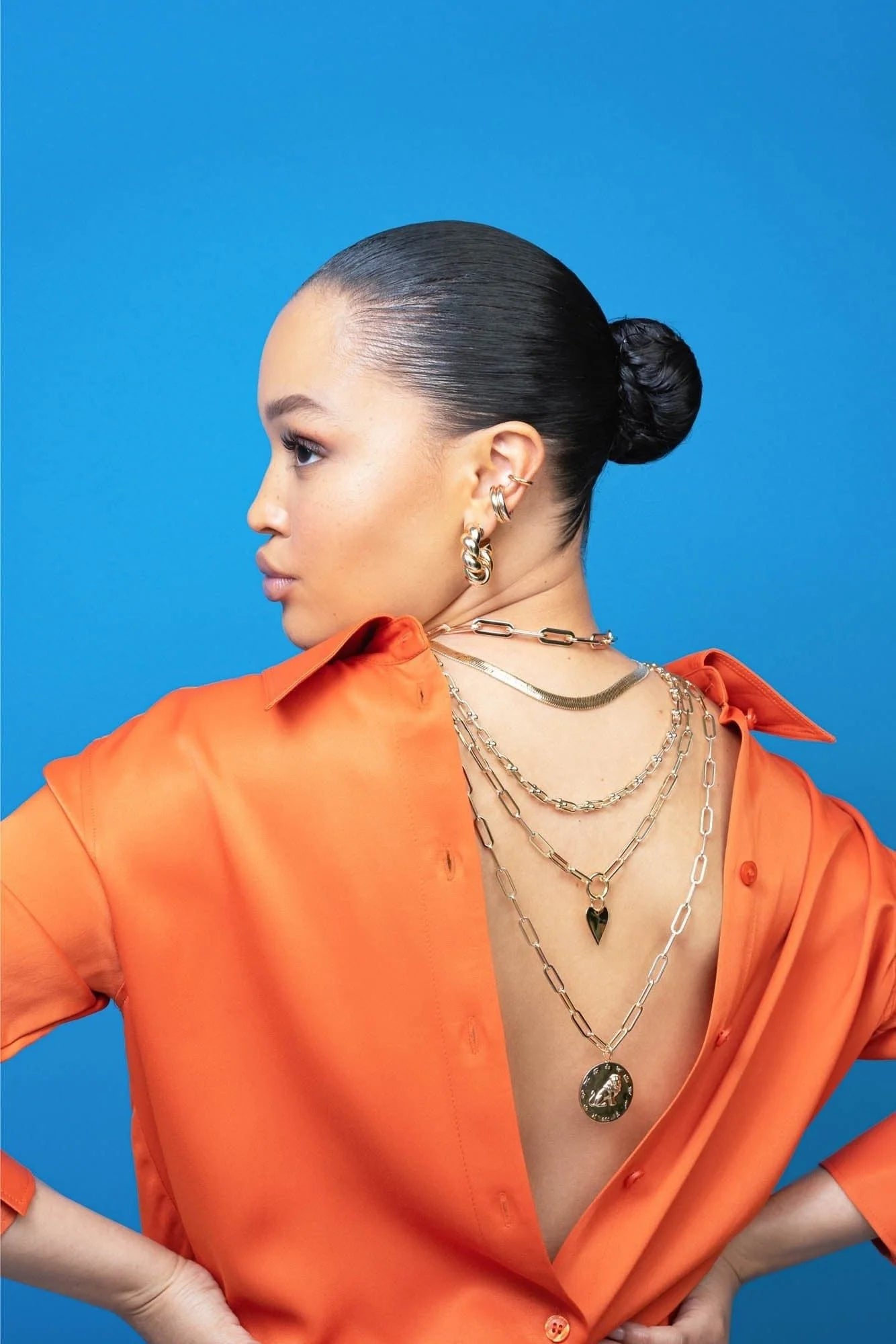 Woman wearing an orange shirt and gold necklaces showcasing a Zodiac Pendant Gemini for Geminis juggle and social groups